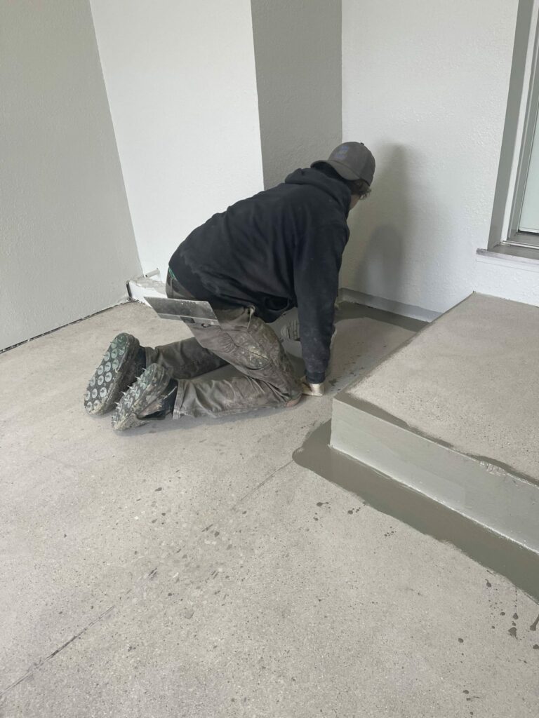 worker finishing concrete floor coating in garage